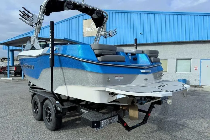 Slide: The Image of 2023 MasterCraft XT22 boat on trailer, blue and silver, parked outside a building. - 8