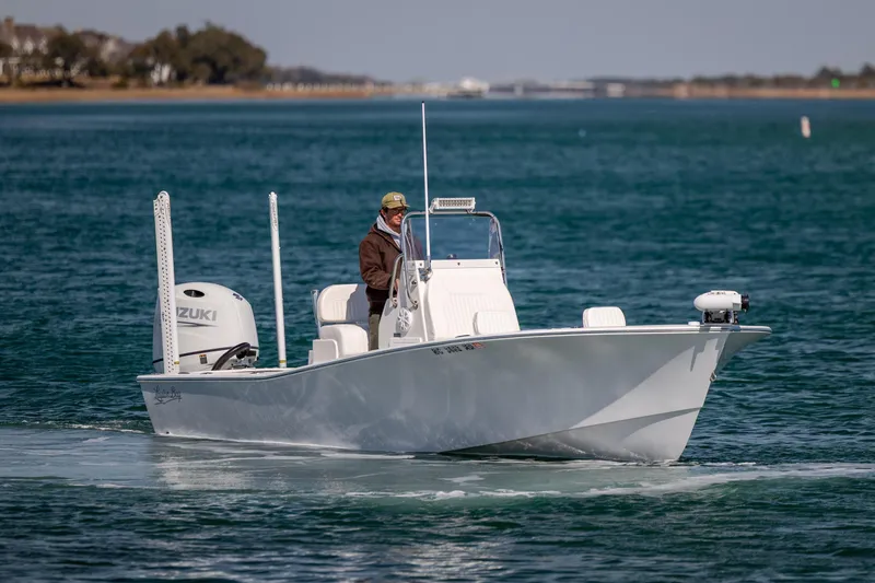 Slide: The Image of 2024 Layton Bay 22 boat cruising on clear blue water with a Suzuki engine. - 2