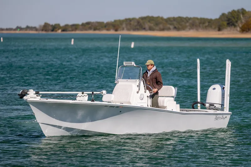 Slide: The Image of 2024 Layton Bay 22 boat cruising on a serene lake with a person onboard. - 3