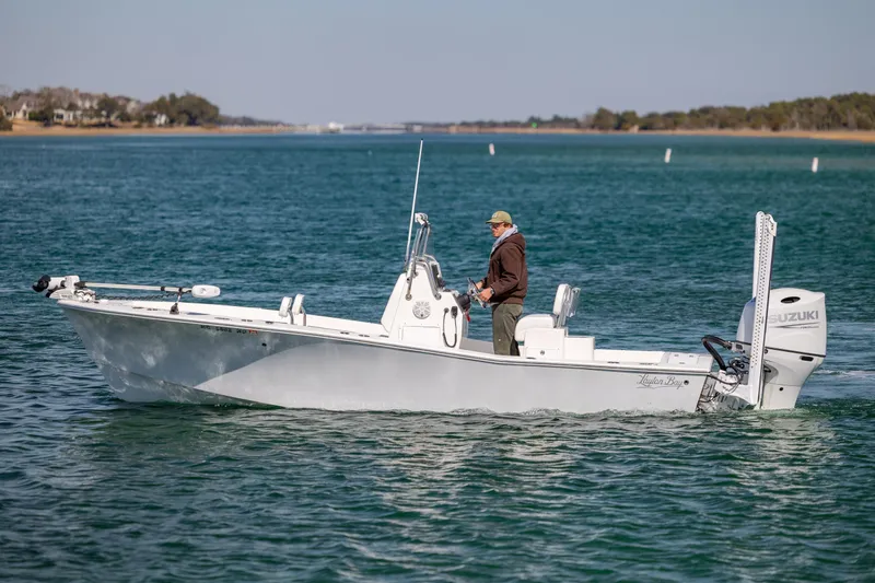 Slide: The Image of 2024 Layton Bay 22 boat cruising on a calm blue lake with a person onboard. - 4