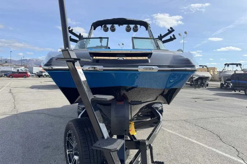 Slide: The Image of 2024 MasterCraft X24 boat on trailer in parking lot under clear sky. - 10