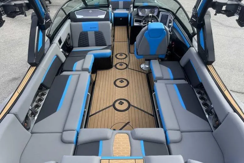 Slide: The Image of 2024 MasterCraft X24 boat interior with blue and gray seating, modern dashboard, and wood-style flooring. - 4
