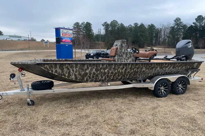 The Image of 2026 Avid 22 Rogue CC boat on trailer, camo design, parked outdoors. - 0