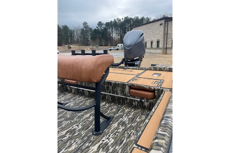 Slide: The Image of 2026 Avid 22 Rogue CC boat with camo design and brown seating, parked outdoors. - 8