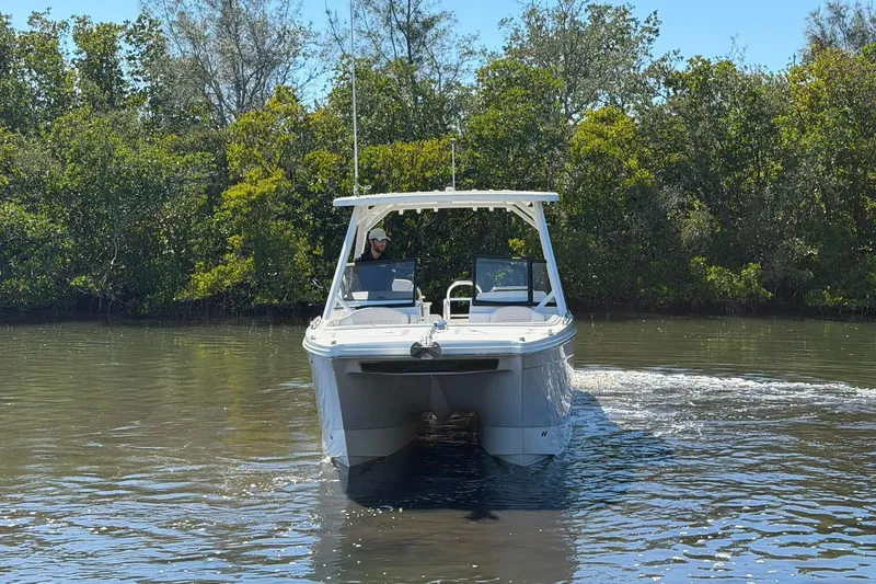 Slide: The Image of 2026 World Cat 265 DC-X boat cruising on a calm river with lush greenery. - 3