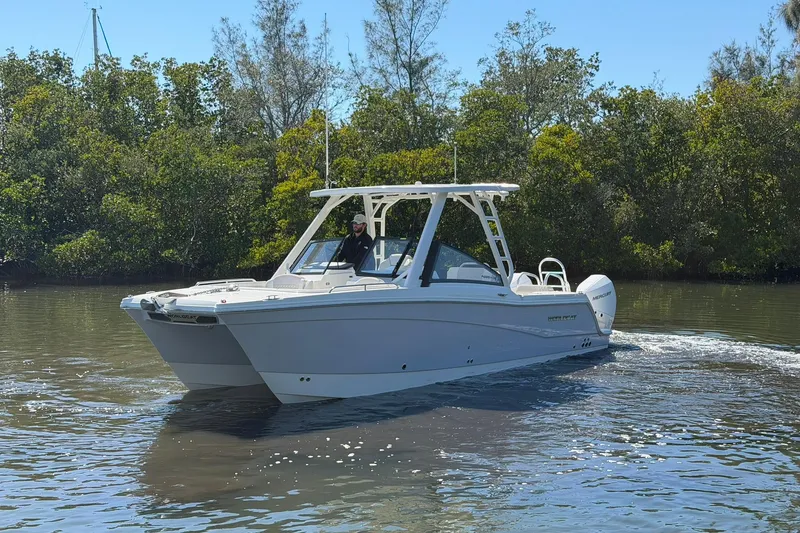 Slide: The Image of 2026 World Cat 265 DC-X boat cruising on a calm river, surrounded by lush greenery. - 4