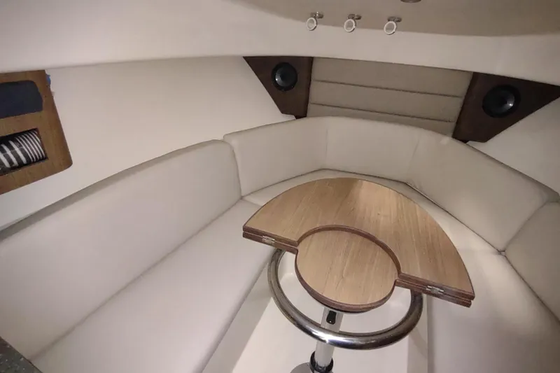 Slide: The Image of 2015 Boston Whaler 285 Conquest cabin interior with beige seating and wooden table. - 3