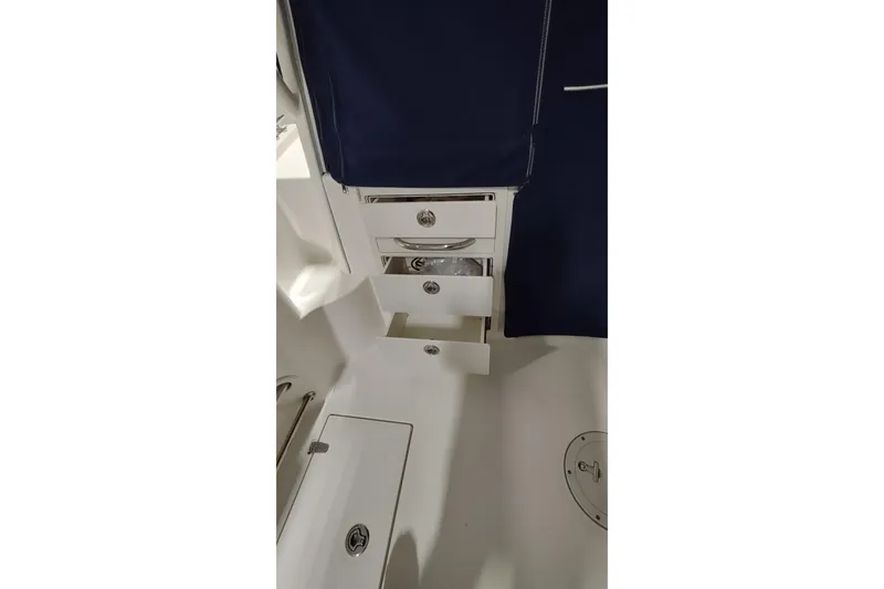 Slide: The Image of 2015 Boston Whaler 285 Conquest interior with open storage drawers and navy curtain. - 31