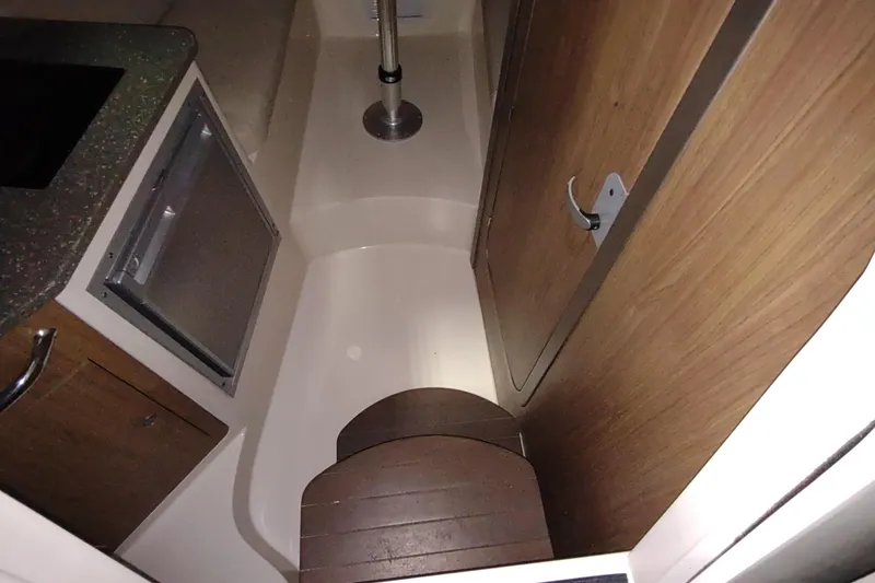 Slide: The Image of 2015 Boston Whaler 285 Conquest cabin interior with wood accents and compact design. - 33