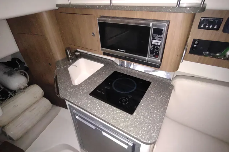 Slide: The Image of 2015 Boston Whaler 285 Conquest galley with microwave, sink, and cooktop. - 35
