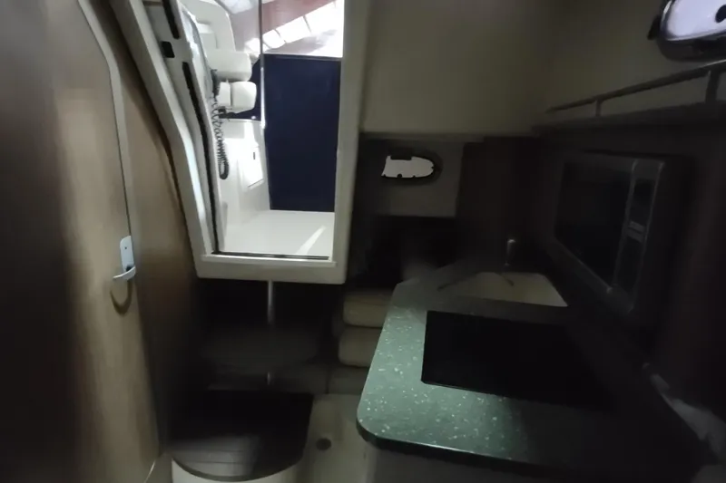 Slide: The Image of Interior of 2015 Boston Whaler 285 Conquest, featuring compact kitchen and seating area. - 46