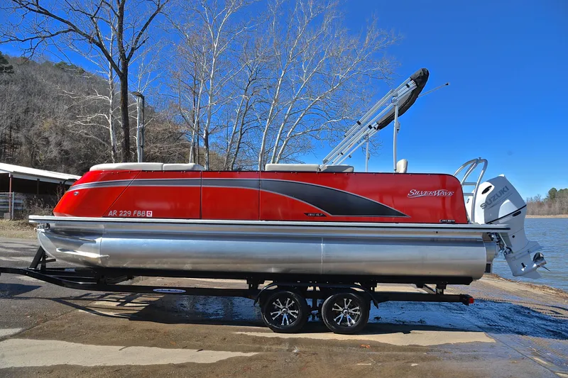 Slide: The Image of 2023 Silver Wave 2210 SW5 RLP pontoon boat on trailer by a lake. - 11