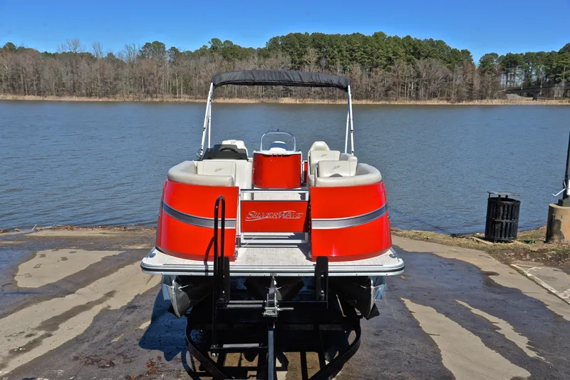 Slide: The Image of Red 2023 Silver Wave 2210 SW5 RLP pontoon boat on a trailer by a lake. - 17