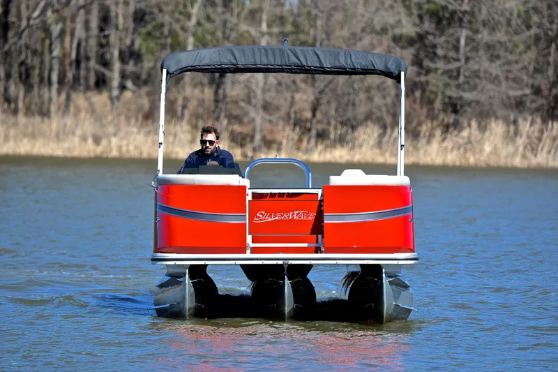 Slide: The Image of 2023 Silver Wave 2210 SW5 RLP pontoon boat on a lake, with a person steering. - 9