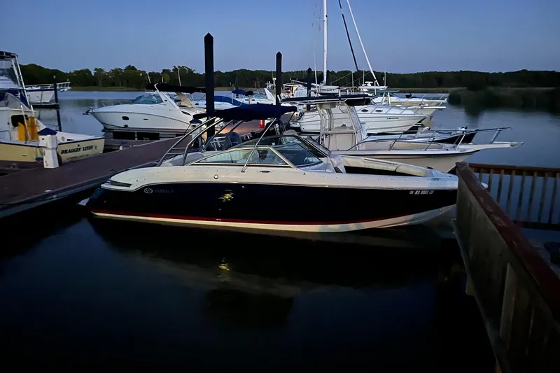 Slide: The Image of 2012 Cobalt 276 boat docked at a marina during twilight, surrounded by other boats. - 1