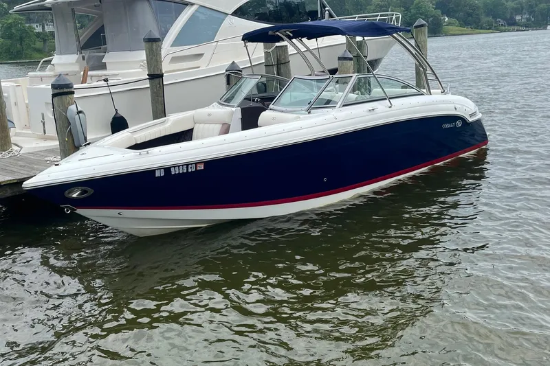 Slide: The Image of 2012 Cobalt 276 boat docked on calm water, featuring sleek design and blue exterior. - 2
