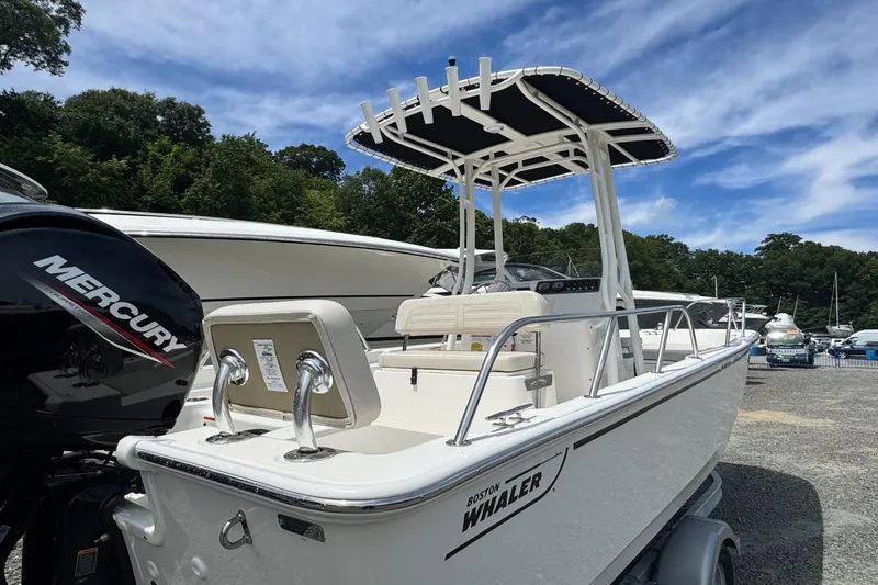 Slide: The Image of Boston Whaler 190 Montauk with T-top and outboard motor, parked with other boats. - 4