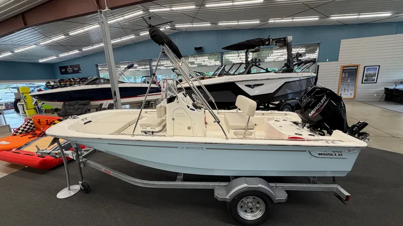Slide: The Image of A 2026 Boston Whaler 150 Montauk sits on a trailer in a showroom. - 1