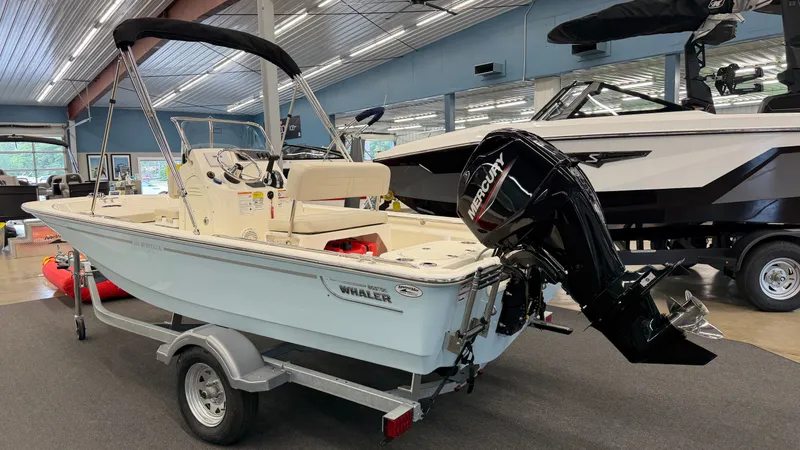 Slide: The Image of Boston Whaler 150 Montauk 2026 in a showroom, on a trailer with an outboard motor. - 3