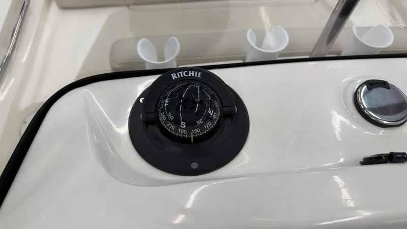 Slide: The Image of A compass on a boat, surrounded by white holders and a metal knob. - 32