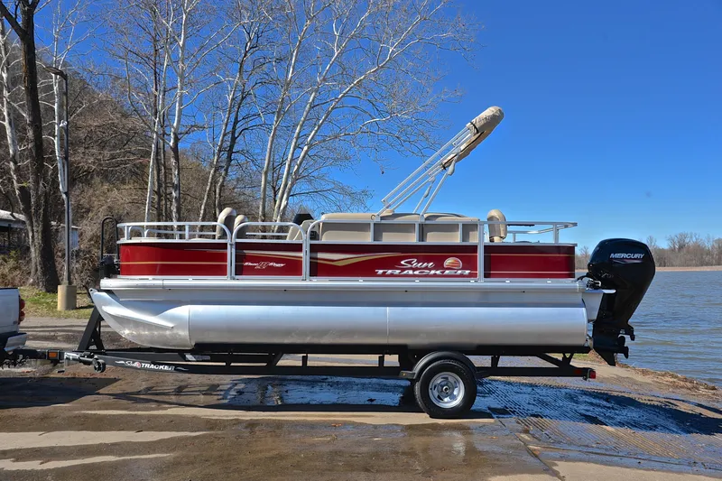 Slide: The Image of 2024 Sun Tracker Bass Buggy 18 DLX pontoon boat on trailer by a lake. - 11