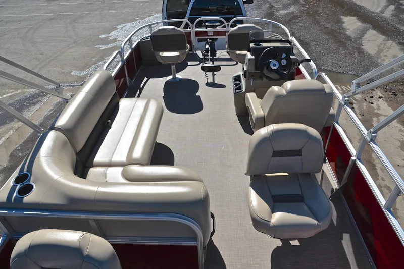 Slide: The Image of 2024 Sun Tracker Bass Buggy 18 DLX pontoon boat interior with beige seating and steering console. - 18