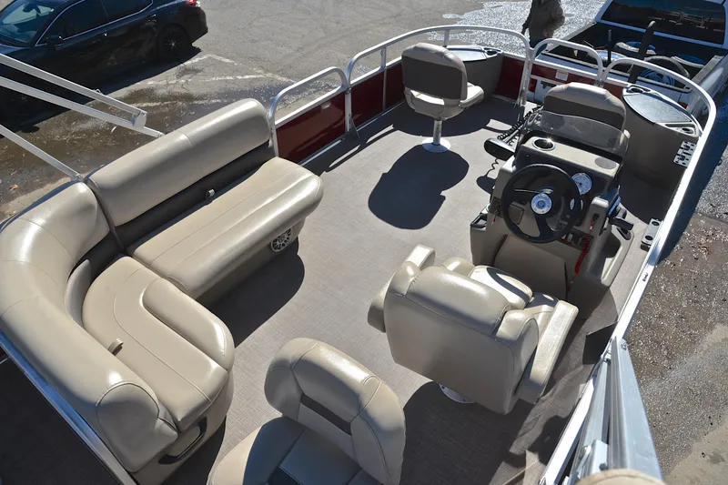 Slide: The Image of 2024 Sun Tracker Bass Buggy 18 DLX pontoon boat interior with beige seating and steering console. - 19