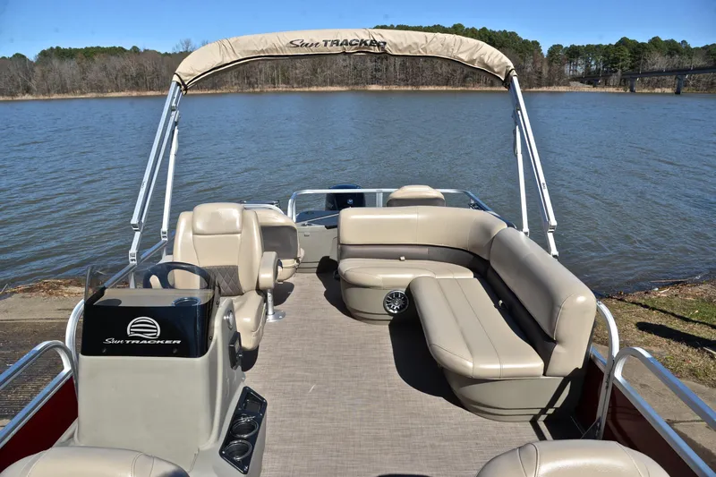 Slide: The Image of 2024 Sun Tracker Bass Buggy 18 DLX pontoon boat on a serene lake. - 20