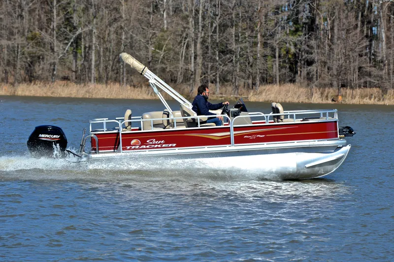 Slide: The Image of 2024 Sun Tracker Bass Buggy 18 DLX pontoon boat cruising on a lake. - 3
