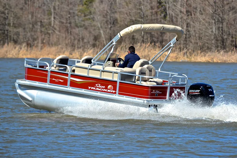 Slide: The Image of 2024 Sun Tracker Bass Buggy 18 DLX pontoon boat cruising on a lake. - 4