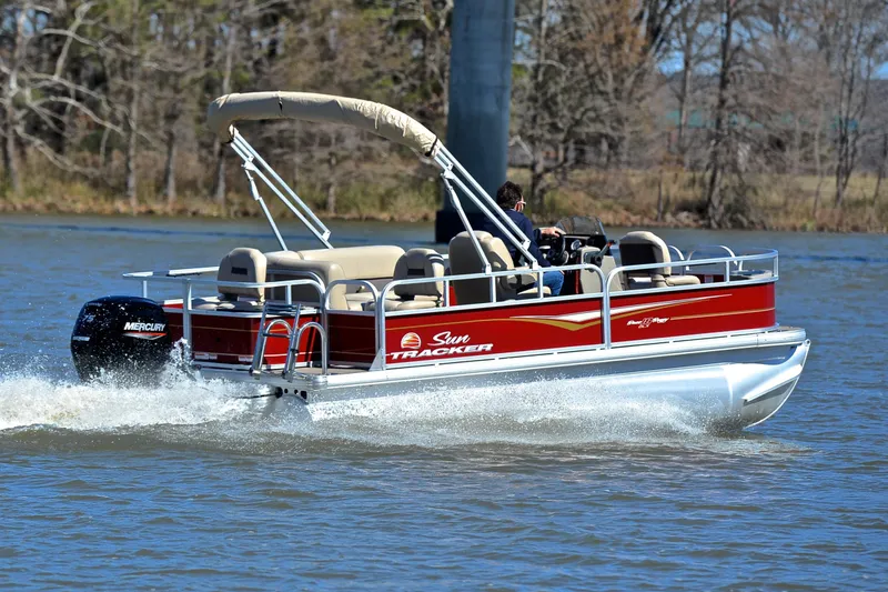 Slide: The Image of 2024 Sun Tracker Bass Buggy 18 DLX pontoon boat cruising on a lake. - 5