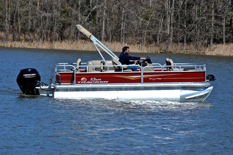 Slide: The Image of 2024 Sun Tracker Bass Buggy 18 DLX pontoon boat cruising on a lake. - 6