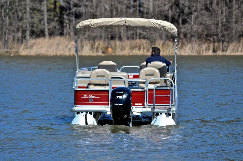 Slide: The Image of 2024 Sun Tracker Bass Buggy 18 DLX pontoon boat cruising on a lake. - 7