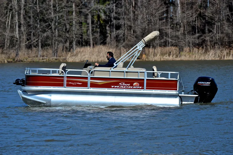 Slide: The Image of 2024 Sun Tracker Bass Buggy 18 DLX pontoon boat cruising on a lake. - 8