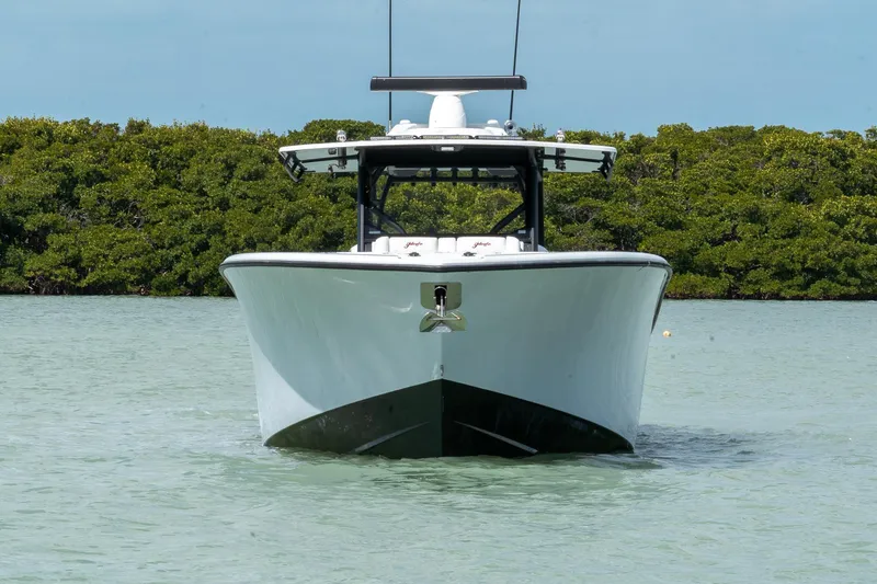 Slide: The Image of 2024 Yellowfin 42 Offshore boat on calm water, front view with lush greenery background. - 1