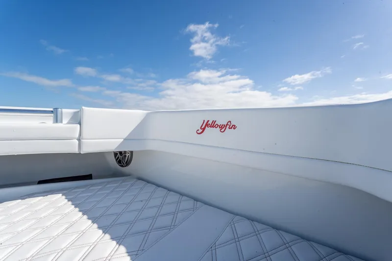 Slide: The Image of 2024 Yellowfin 42 Offshore boat interior with white seating and blue sky background. - 17