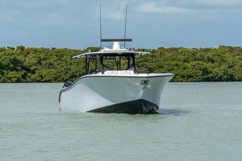 Slide: The Image of 2024 Yellowfin 42 Offshore boat cruising on calm water near lush greenery. - 2