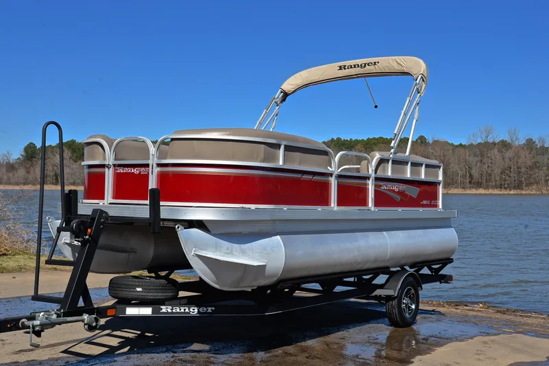 Slide: The Image of 2021 Ranger 180 Reata pontoon boat on trailer by a lake. - 10