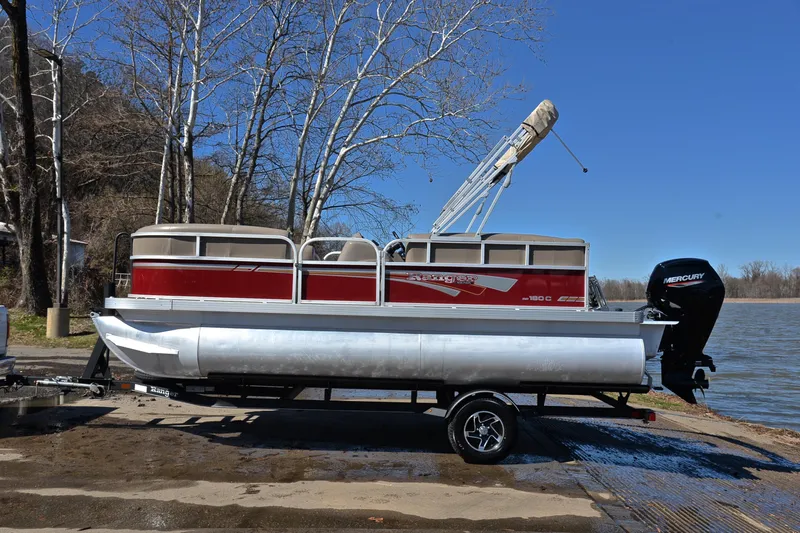 Slide: The Image of 2021 Ranger 180 Reata pontoon boat on trailer by a lake, clear blue sky. - 11