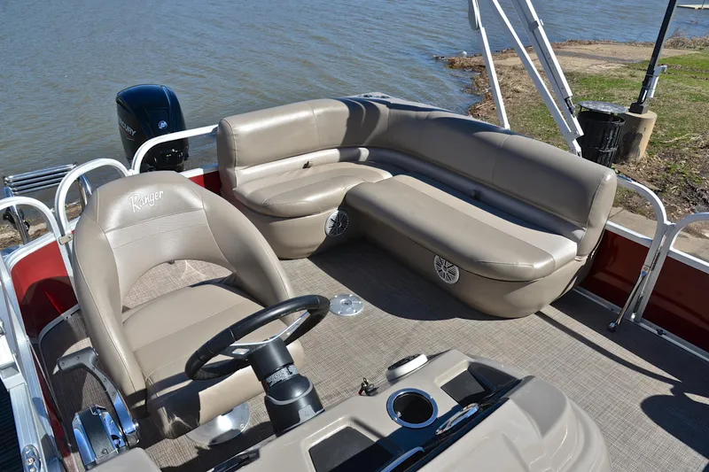Slide: The Image of 2021 Ranger 180 Reata boat interior with beige seating, steering wheel, and lake view. - 22