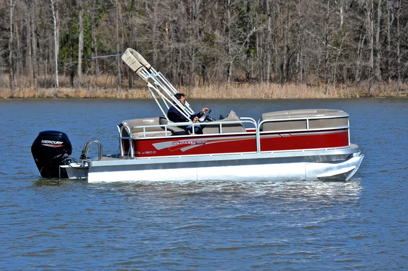 Slide: The Image of 2021 Ranger 180 Reata pontoon boat cruising on a lake with trees in the background. - 6