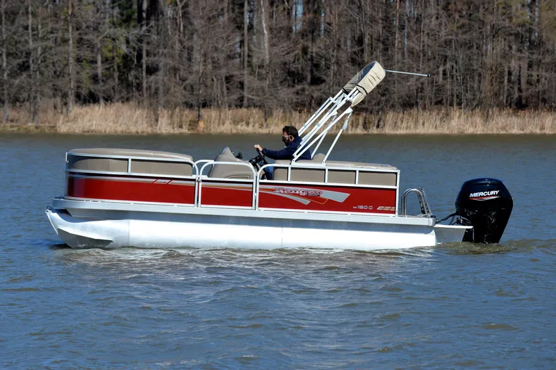 Slide: The Image of 2021 Ranger 180 Reata pontoon boat cruising on a lake with trees in the background. - 8