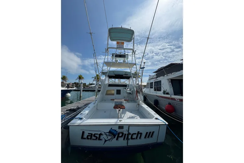 Slide: The Image of 1963 Bertram 31 Sportfisher boat docked, named "Last Pitch III," under a partly cloudy sky. - 21