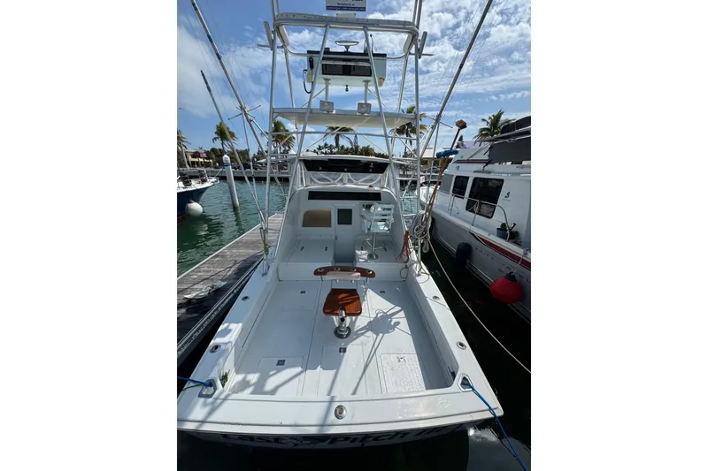 Slide: The Image of 1963 Bertram 31 Sportfisher boat docked, featuring spacious deck and fishing chair. - 23