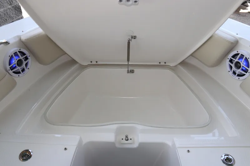 Slide: The Image of 2026 Robalo R207 Dual Console boat storage compartment with speakers and open hatch. - 27