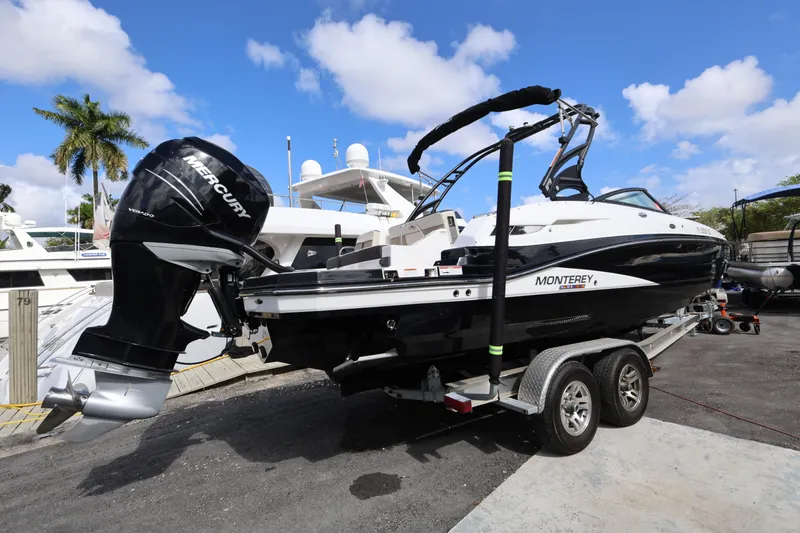 Slide: The Image of 2021 Monterey M-65 boat on trailer with Mercury engine, dockside under blue sky. - 2