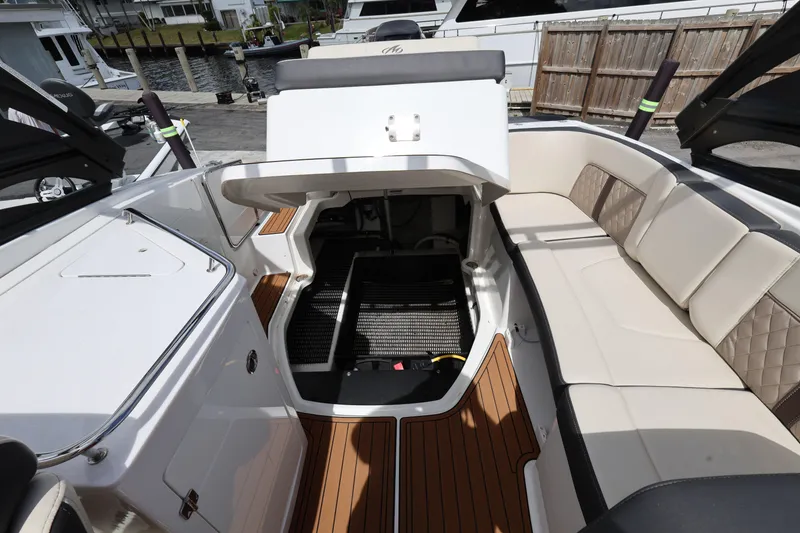 Slide: The Image of 2021 Monterey M-65 boat interior with open storage, beige seating, and wood accents. - 22