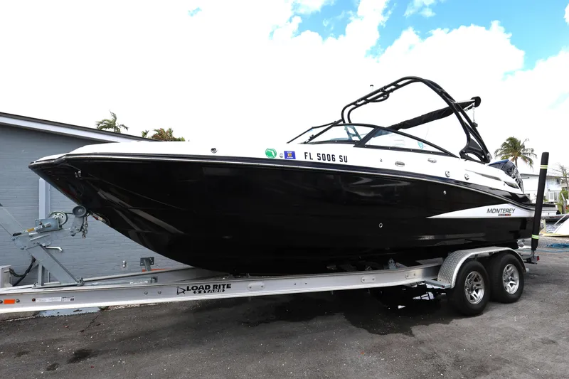 Slide: The Image of 2021 Monterey M-65 boat on trailer, black hull, parked outdoors. - 3