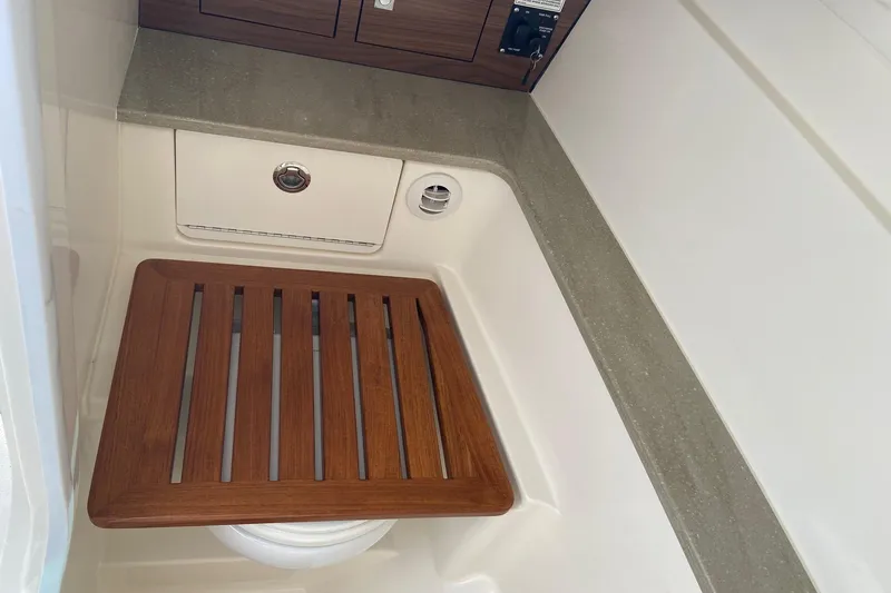 Slide: The Image of 2024 Boston Whaler 320 Vantage interior with wooden seat and storage compartment. - 13