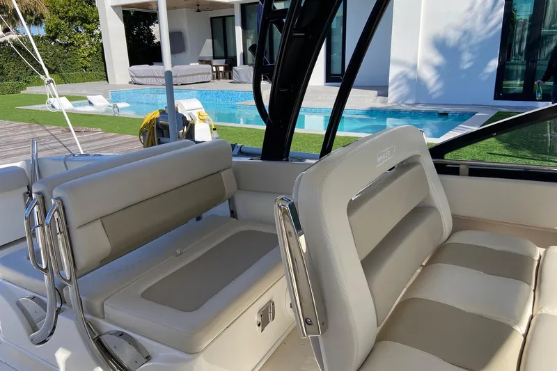 Slide: The Image of 2024 Boston Whaler 320 Vantage boat interior near a modern poolside setting. - 23